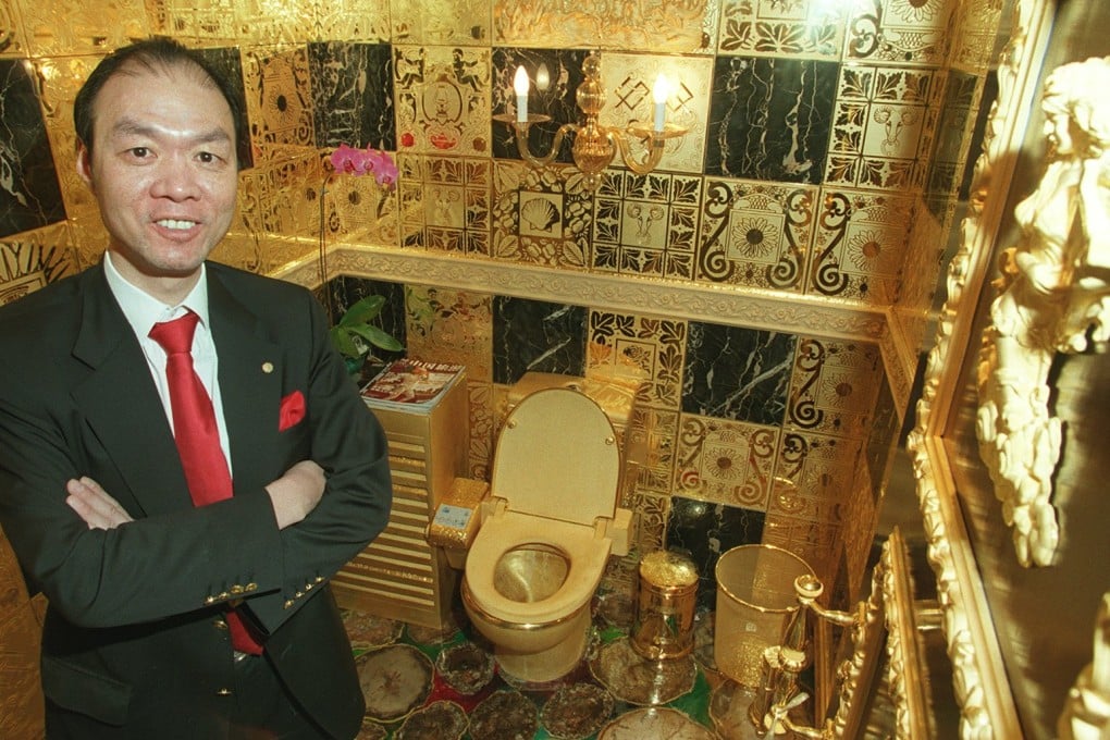 Winger Lam Sai-wing, chairman of Hang Fung Gold Technology Group, poses with one of two solid gold toilets at his Hung Hom store. Photo: Dickson Lee