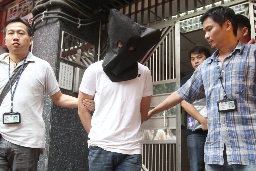 An alleged triad member is arrested in Tsuen Wan. The black hood is used to protect the suspect's privacy. Photo: Edward Wong/SCMP