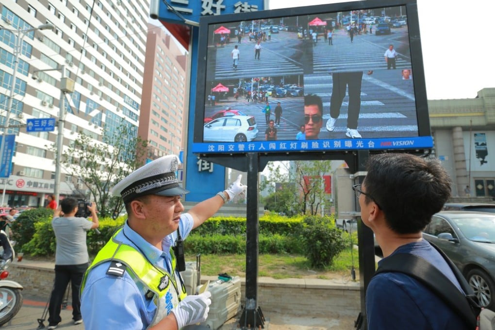 A policeman shows a man that he's been caught jaywalking on a screen besides a road in Shenyang. (Source: China Foto Press)