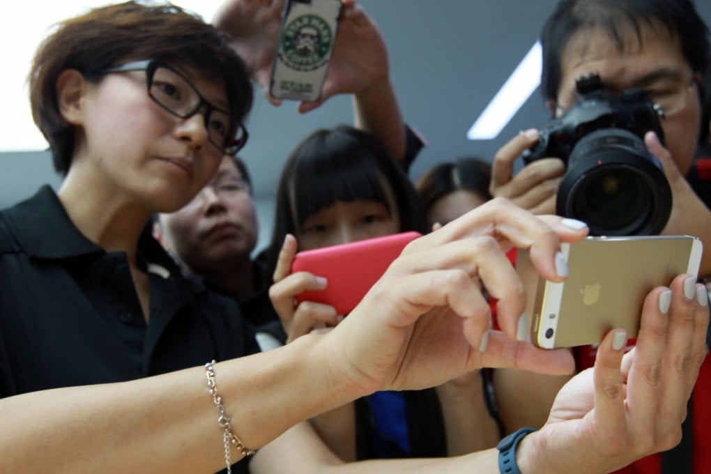 An Apple Store saleswoman holds a gold iPhone in Beijing on September 11, 2013. (Picture: SCMP)