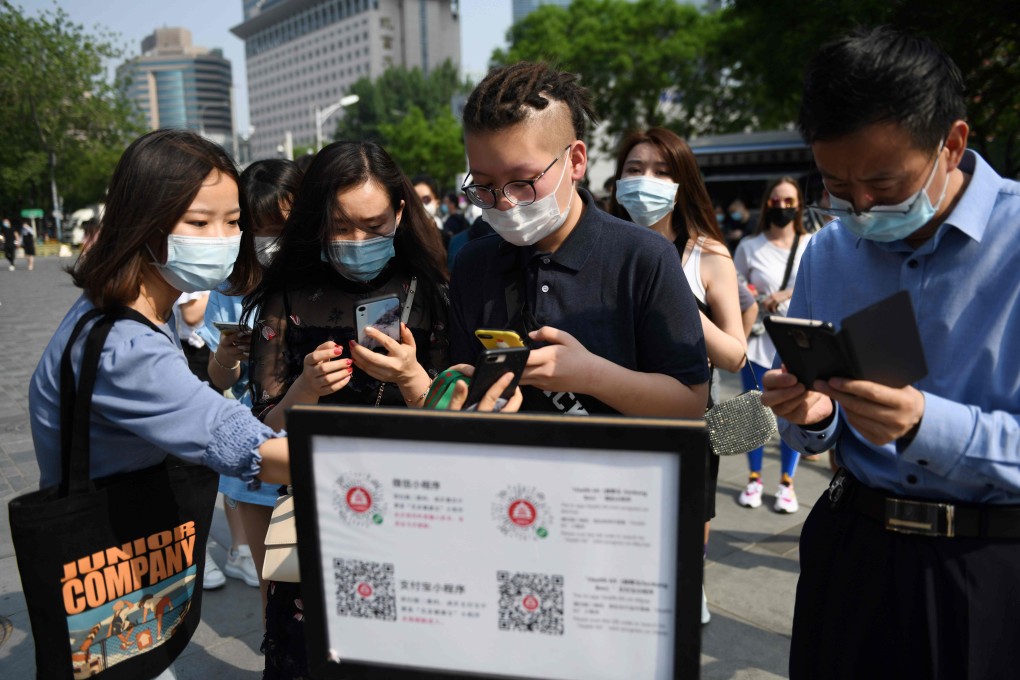People scan a code to bring up a phone app that generates a health code before they enter a shopping mall in Beijing on May 2. (Picture: Greg Baker/AFP)