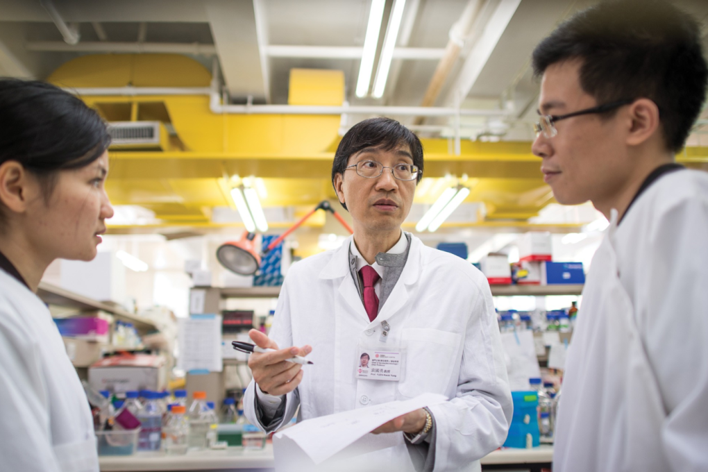 Professor YUEN Kwok-yung discusses with students in a laboratory.