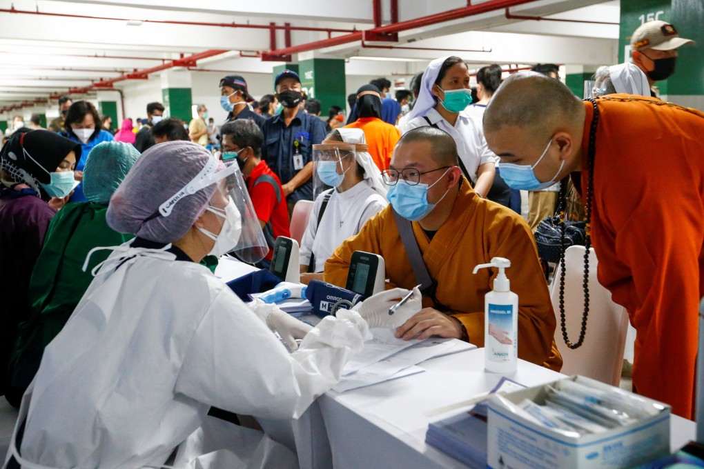 Monks and nuns talk to health care workers before receiving their first dose of China’s Sinovac Biotech vaccine, at the parking lot of the Grand Istiqlal Mosque in Jakarta, Indonesia, on February 25. Photo: Reuters