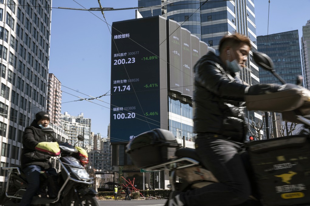 Motorists travel past a screen displaying stock figures in Shanghai, China. Photo: Bloomberg