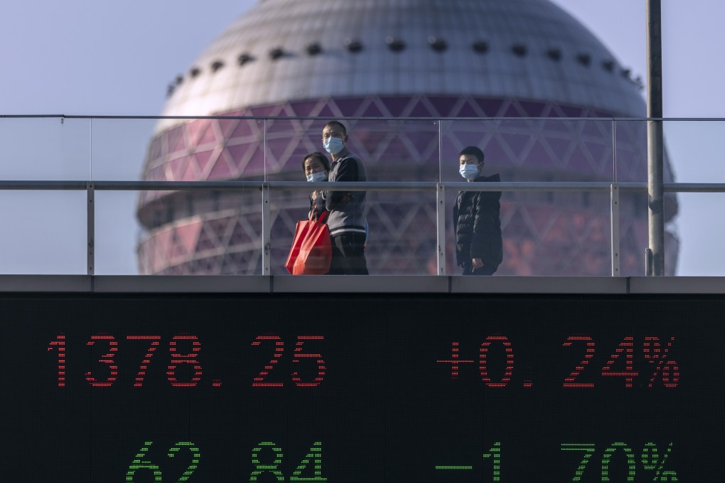 People walk over a bridge displaying stock prices in Shanghai’s financial district. Photo: EPA-EFE