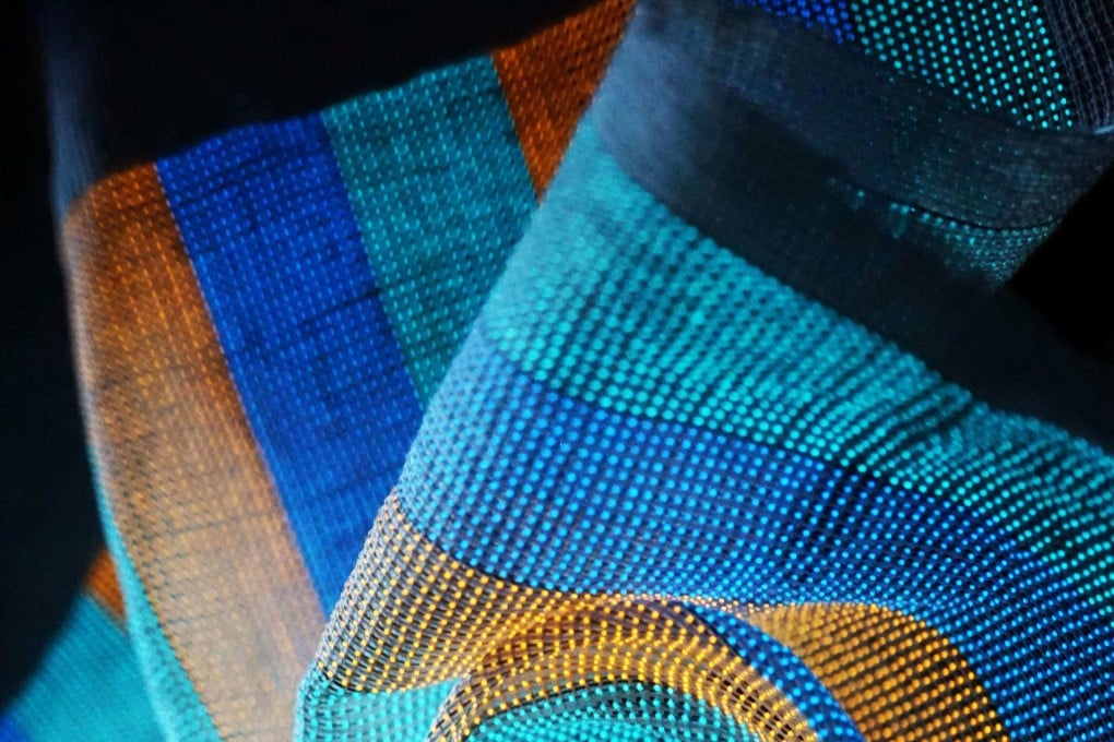 The multicoloured textile under distortion, which is wearable, foldable and washable, but also has a fully functioning display. Photo: AFP