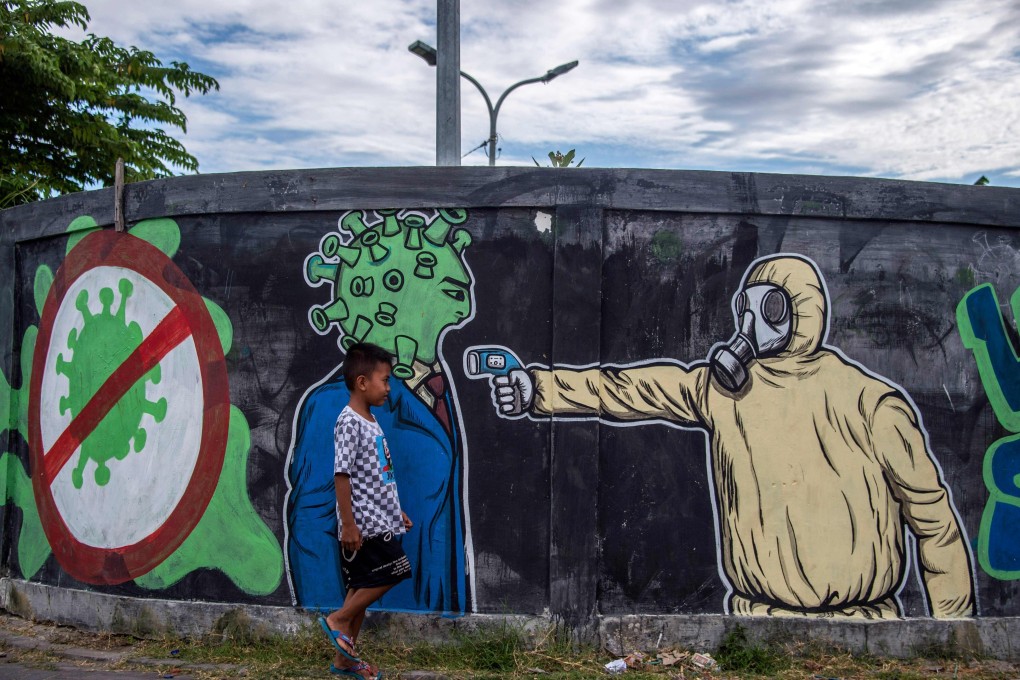 A boy walks past a mural depicting the fight against Covid-19 in Surabaya, Indonesia. Photo: AFP