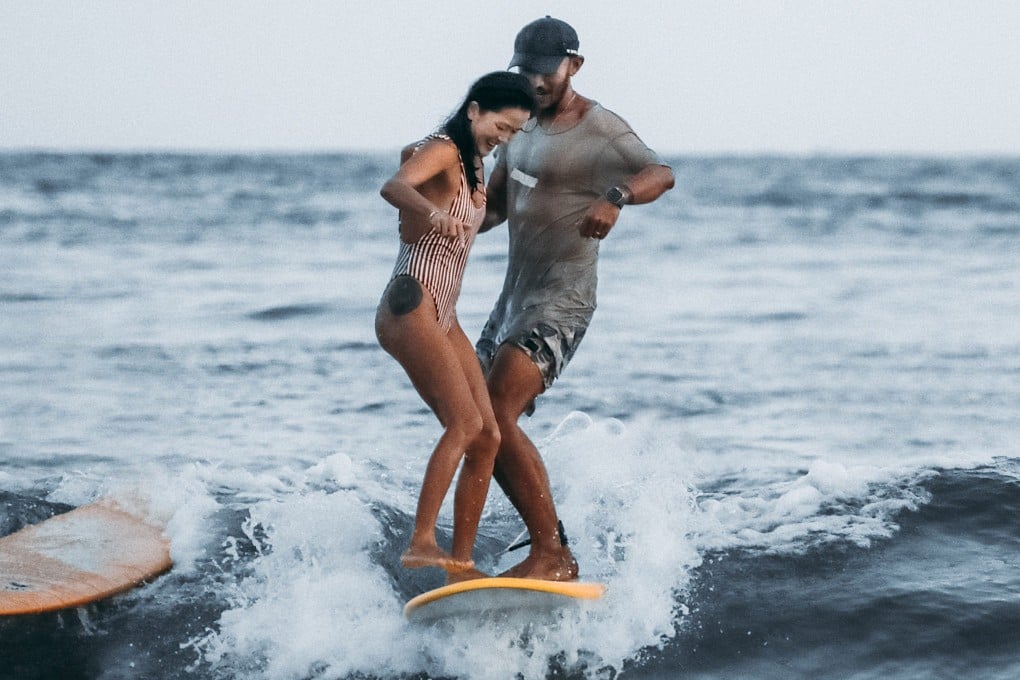Chinese surfer Monica Guo and surfing instructor Justin Tian share a surfboard in Hainan, China. Women make up almost three quarters of the clientele at surf schools run by Tian. Photo: Courtesy of Justin Tian