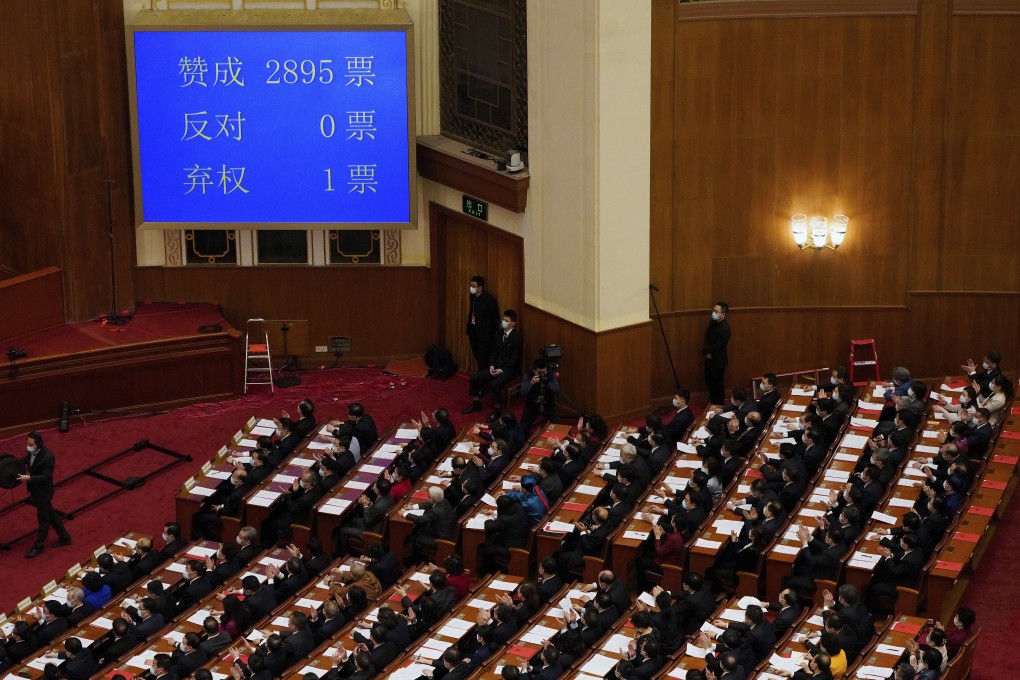 Delegates applaud near a screen showing number of votes for support of the plan to give a pro-Beijing committee power to appoint more of Hong Kong’s lawmakers, during the closing session of the National People’s Congress (NPC) in Beijing, on March 11. Photo: AP