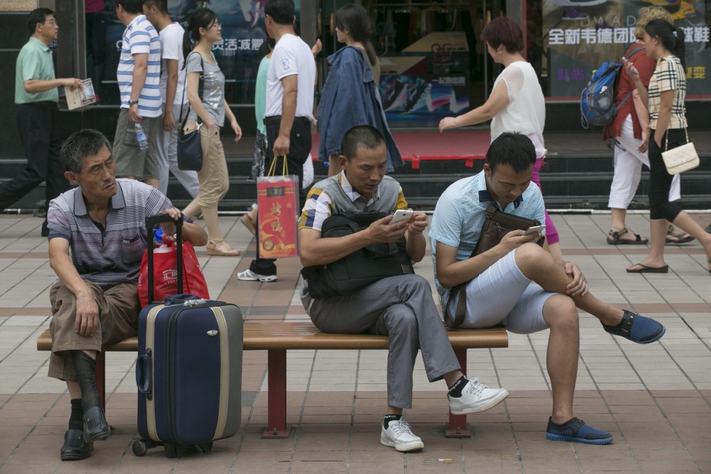 People play with their smartphones at a shopping district in Beijing, China, on July 23, 2014. Photo: EPA