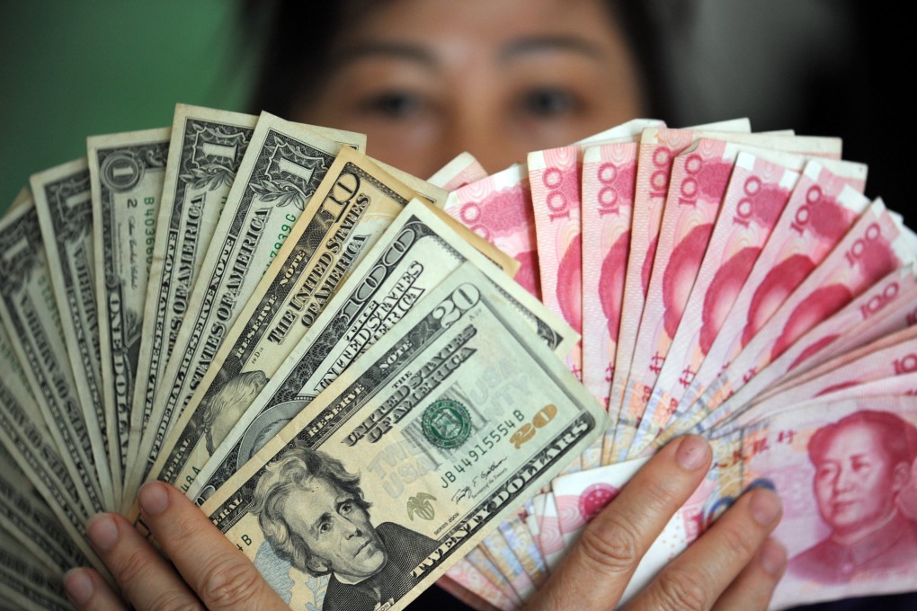 A woman holds up US dollar and Chinese renminbi banknotes in Qionghai, in south China’s Hainan province, on January 7, 2016. Photo: Xinhua