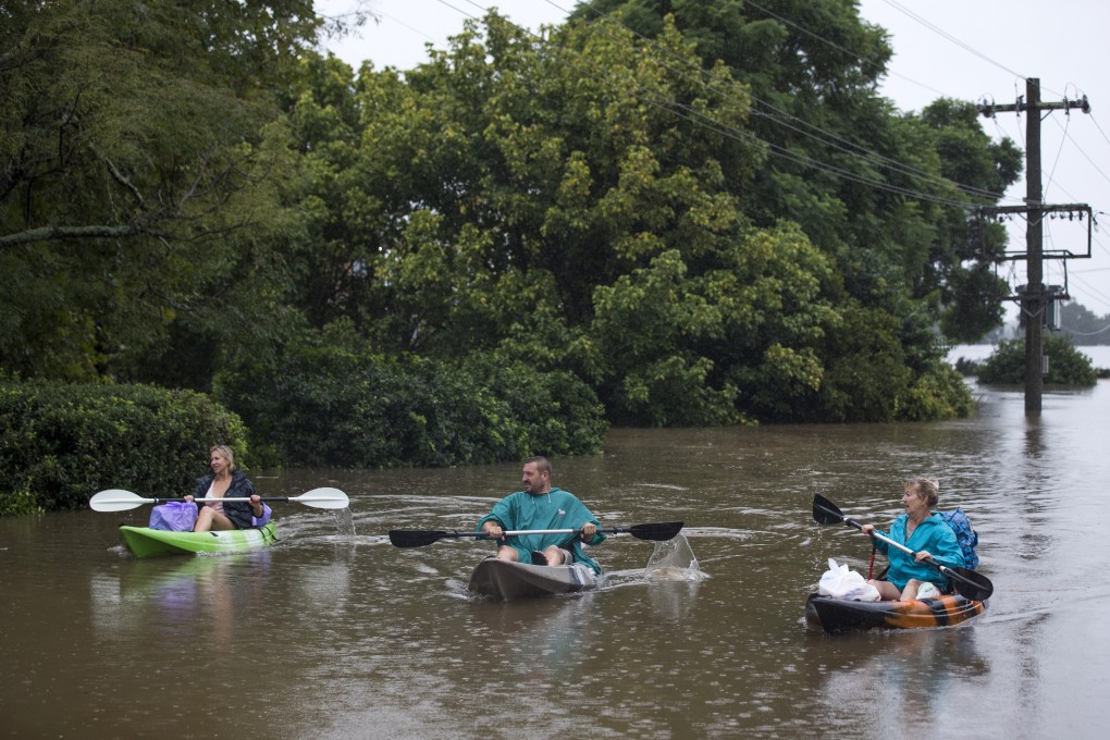 Residents transport household items on kayaks along a street submerged in floodwaters in Windsor, Sydney. Photo: Bloomberg