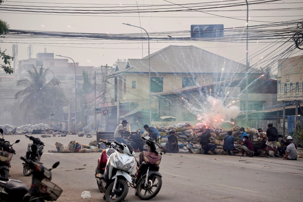Firecrackers explode as protesters take cover behind a barricade during a demonstration in Mandalay. Photo: Reuters