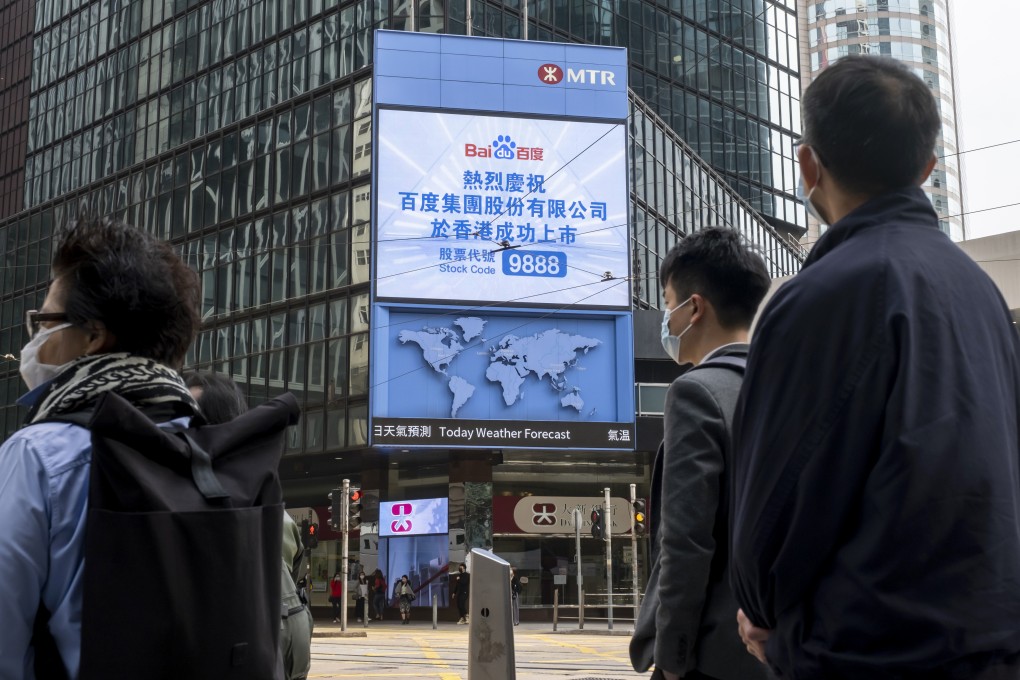 Pedestrians stand in front of a screen showing a message marking the listing of Baidu Inc. on the Hong Kong stock exchange on March 23. Photo: Bloomberg