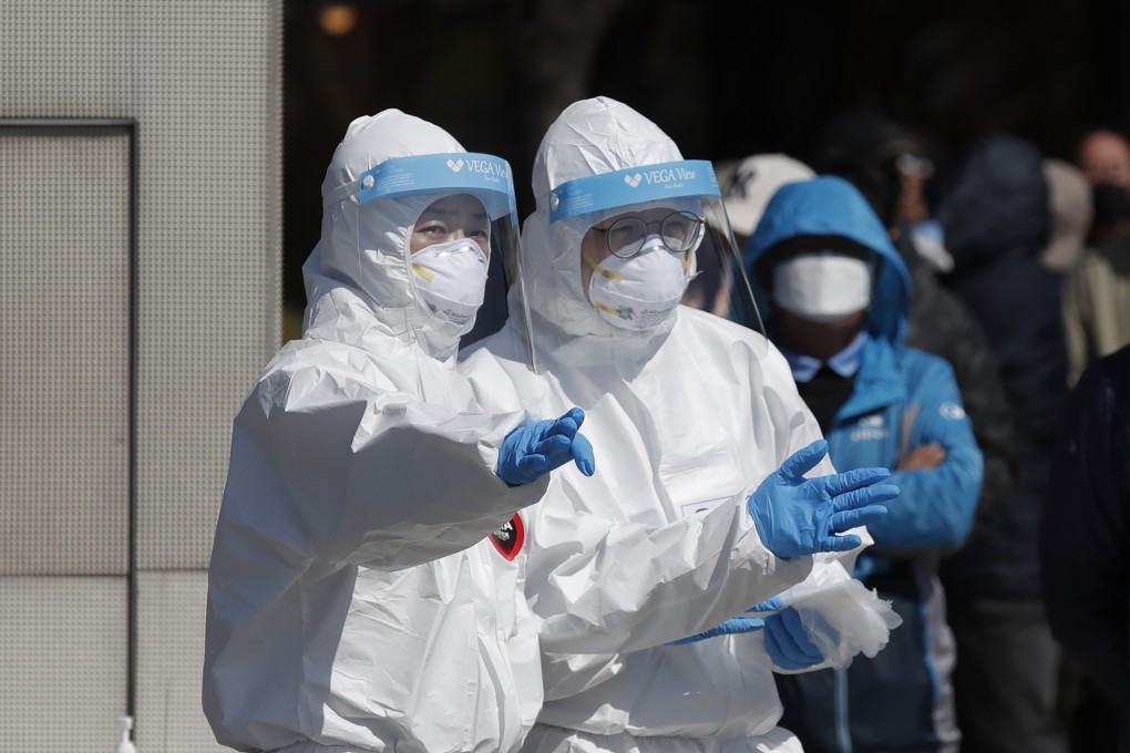 Health officials wearing protective suits talk at a coronavirus testing site in Seoul. Photo: AP