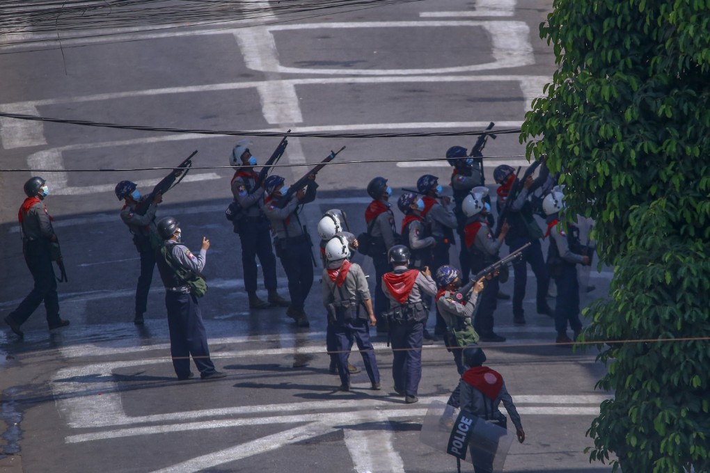 Police officers aim guns towards people in nearby apartments as they stand off with anti-coup protesters in Yangon, Myanmar. Photo: AP