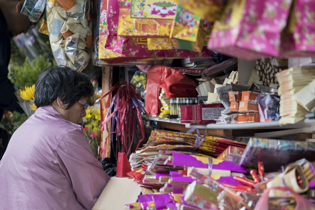 A shop owner sells paper offerings and joss papers which are produced to be burnt as offering to the dead. Photo: Getty