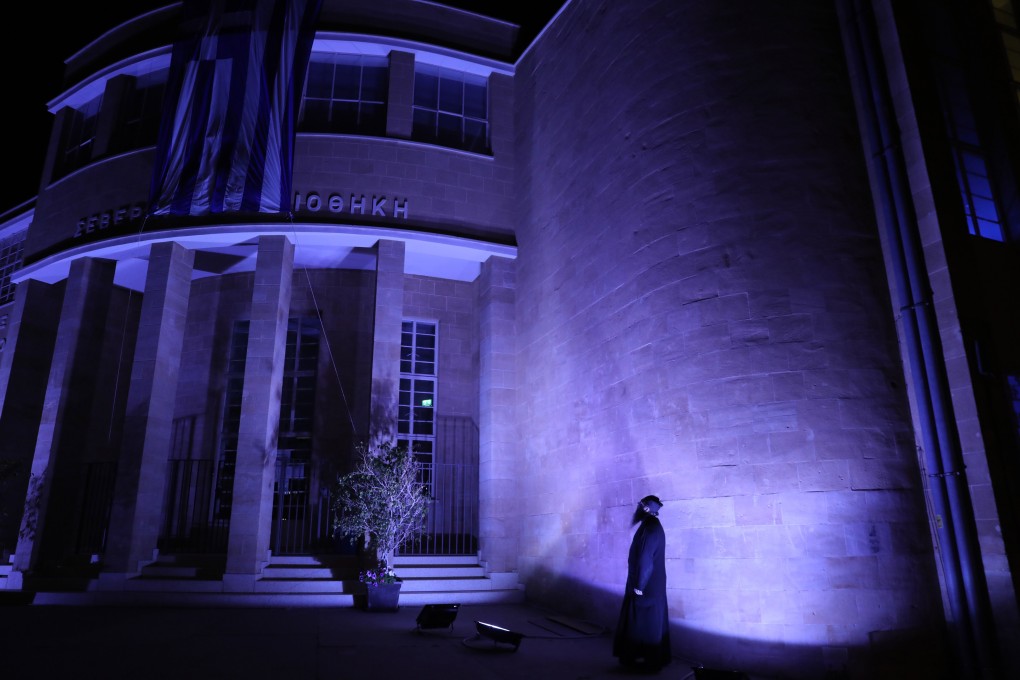 A priest looks at the illuminated building of Severios library in Nicosia, Cyprus on Tuesday. Photo: EPA-EFE