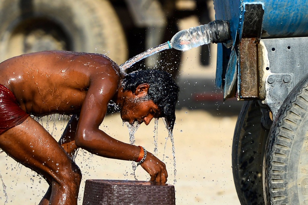 An Indian truck driver takes a bath using a water tanker. Photo: AFP