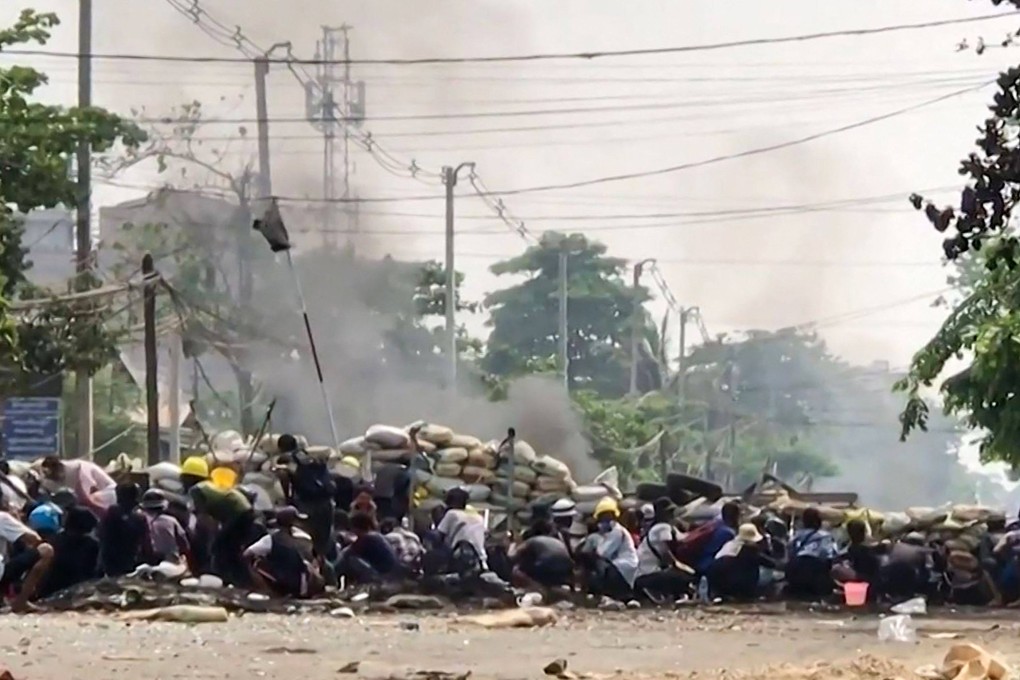Protesters in Myanmar hiding behind a makeshift barricade in Yangon. Photo: AFP
