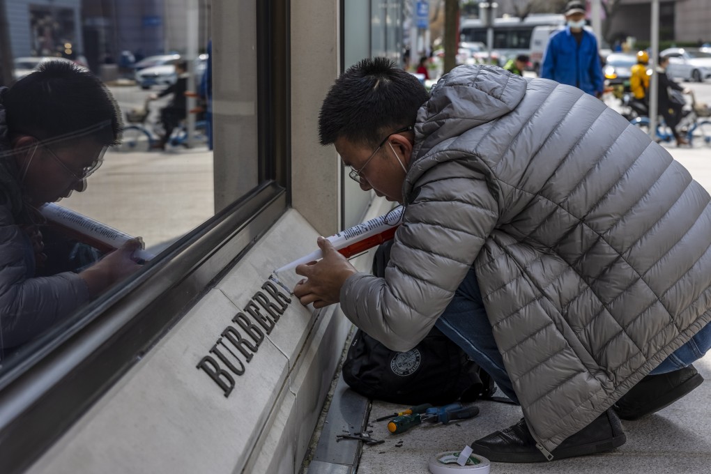 A man repairs a damaged logo in front of a Burberry store in Shanghai on March 26. The British designer was the first luxury brand to be targeted in China in a backlash against Western sanctions imposed over alleged human rights abuses in the Xinjiang region, after retailers including H&M and Nike were boycotted by Chinese shoppers over voicing concerns about cotton sourced from the Chinese region. Photo: EPA-EFE