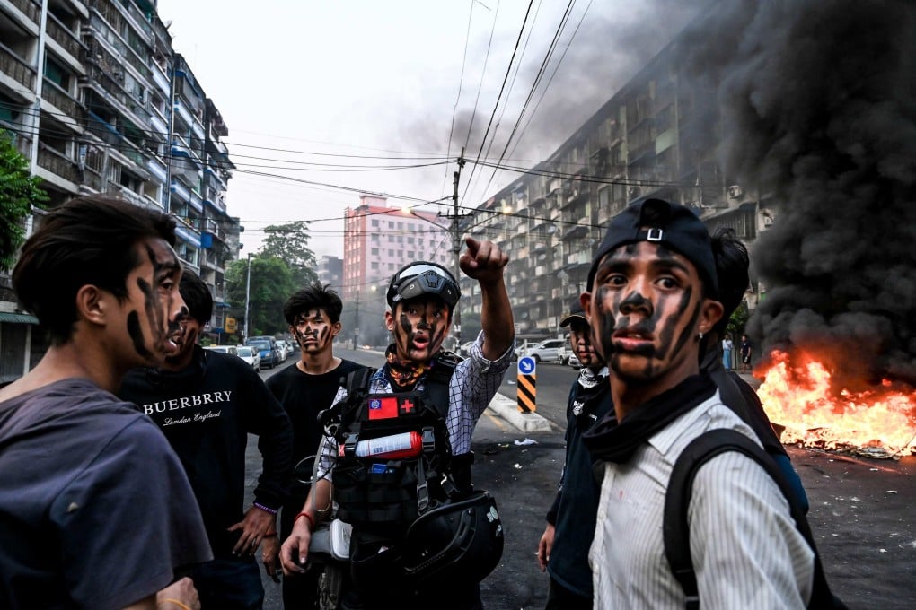 A paramedic in Yangon gestures as he talks to protesters with their faces painted near a burning makeshift barricade during a protest on March 30, 2021. Photo: AFP