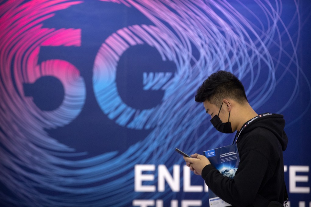 A man looks at his smartphone as he walks past a sign advertising 5G services at an expo in Beijing on September 14, 2020. Photo: AP