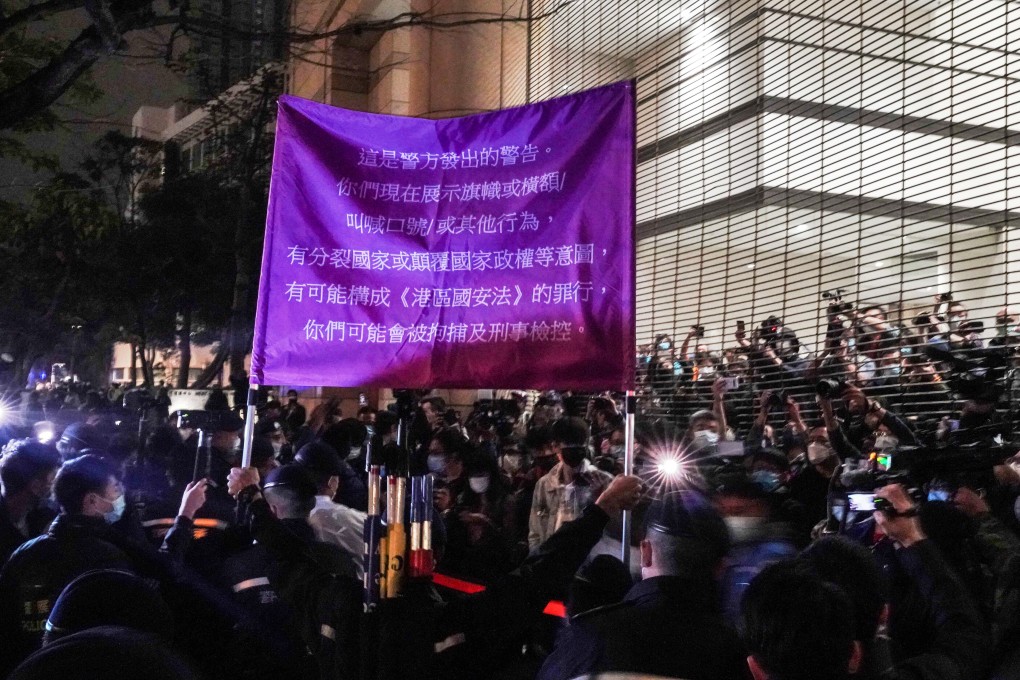 Police officers warn supporters of 47 pro-democracy activists they are violating the national security law outside the West Kowloon Magistrates’ Courts on March 4. Photo: Felix Wong