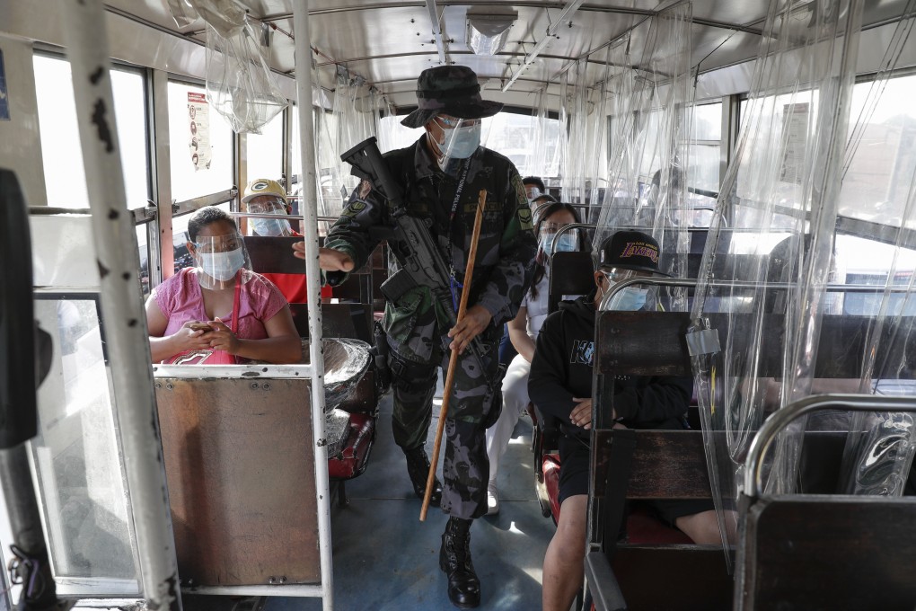 An armed policeman checks a passenger bus during the new lockdown to prevent the spread of Covid-19 in Metro Manila. Photo: AP