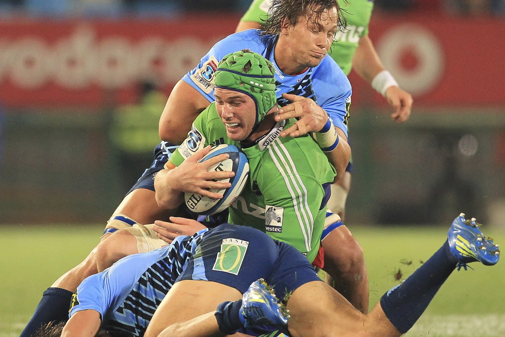 FILE - In this May 18, 2013, file photo, New Zealands Highlanders Joe Wheeler, front, is tackled by South Africas Bulls JJ Engelbrecht, bottom, and teammate Arno Botha, second from the bac, during their Super Rugby match at Loftus Versfeld Stadium in Pretoria, South Africa. Wheeler, a New Zealand television rugby commentator who adopted a mock Asian accent during a post-game interview on Friday, April 2, 2021 is likely to keep his job despite an outpouring of public criticism. (AP Photo/Themba Hadebe, File)