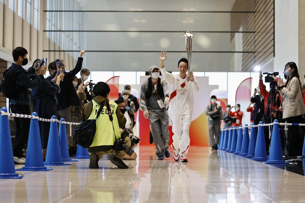 A Tokyo Olympic torch relay runner passes through an office building in Nagoya, Japan. Photo: Kyodo