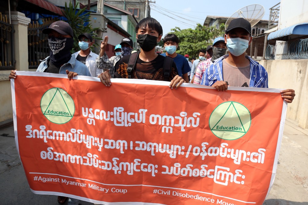 Demonstrators in Mandalay hold a banner criticising the junta. Photo: EPA