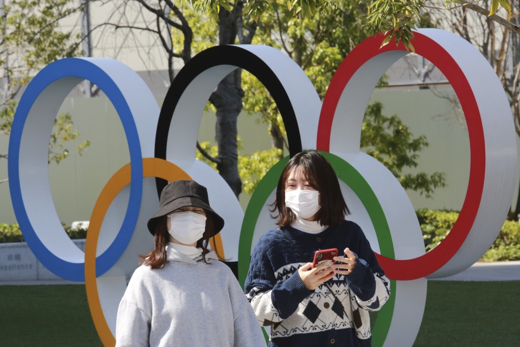 People walk past the Olympic rings in Tokyo. Photo: AP