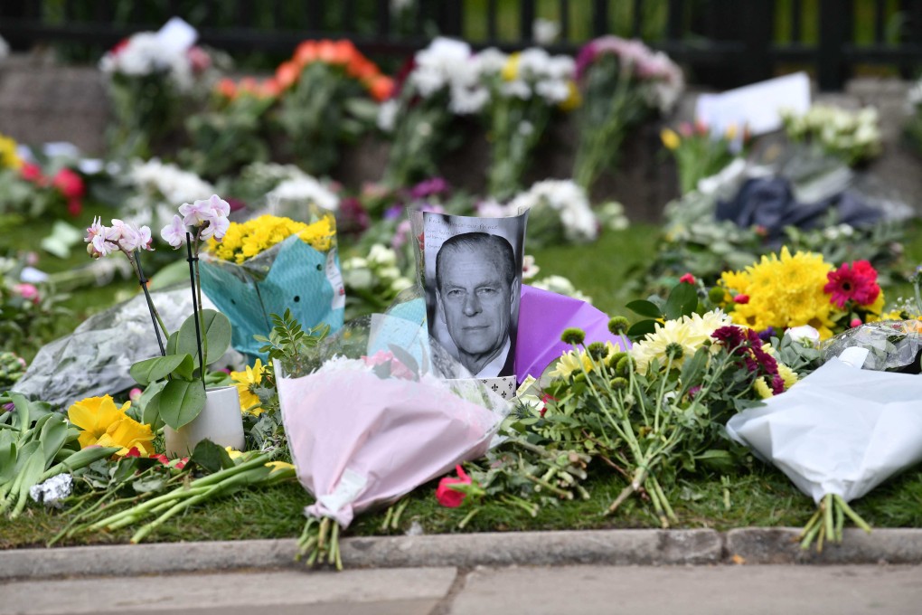 A photo of Britain’s Prince Philip, Duke of Edinburgh, is positioned among floral tributes outside Windsor Castle near London on Saturday. Photo: AFP
