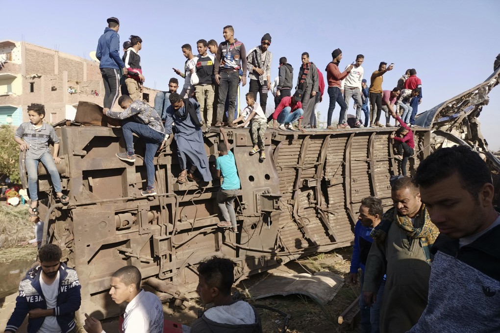 Egyptians gather around mangled train carriages at the scene of a train accident that killed at least 18 people on March 26. Photo: AP