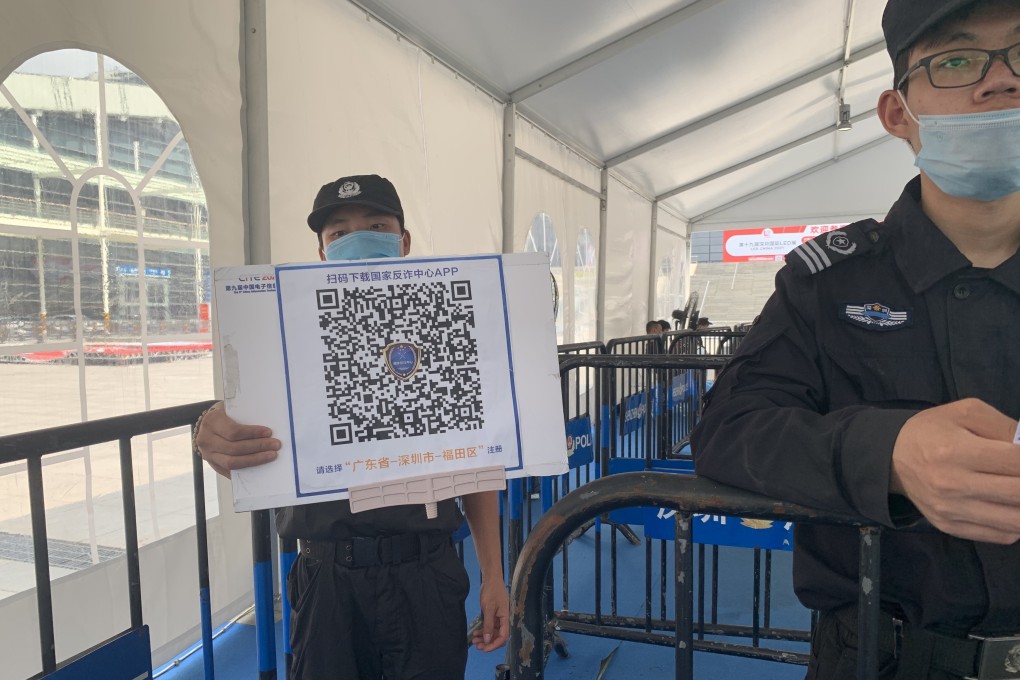 A security guard holds a sign with a QR code for visitors to scan and download a new official anti-fraud app at the entrance of the Shenzhen Convention and Exhibition Center on April 12, 2021. Photo: Yujie Xue