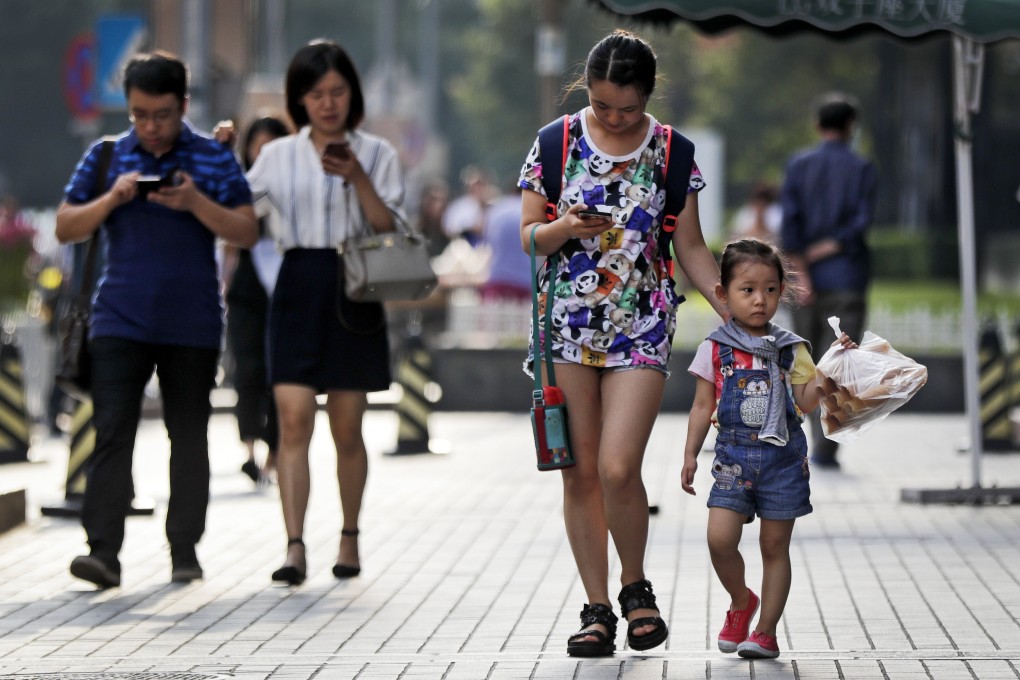 Pedestrians view their smartphones as they walk along a sidewalk in Beijing on Wednesday, Aug. 9, 2017. Photo:: AP
