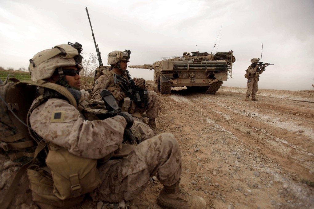 US marines patrol past a Danish army tank as they clear improvised explosive devices on the outskirts of Marjah town in Afghanistan on February 21, 2010. Photo: AFP