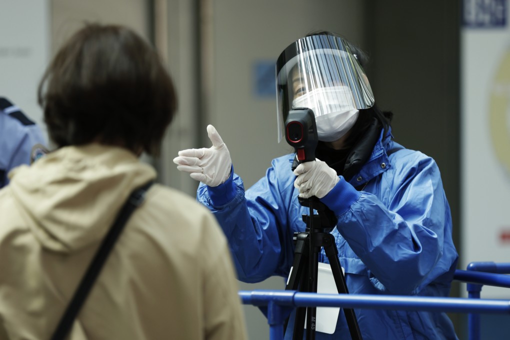 A Japanese worker takes a person’s temperature at an event in Osaka. Photo: AP