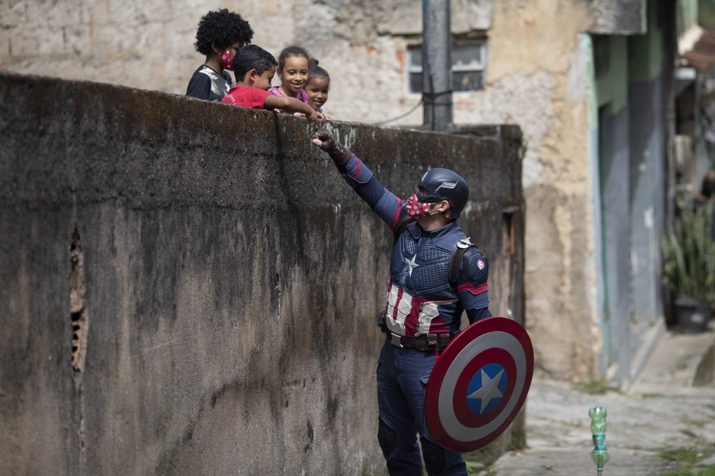 Military police officer Everaldo Pinto, dressed as Captain America, advises children on the need to protect themselves against Covid-19, in Petropolis, Rio de Janeiro state, Brazil. Photo: AP