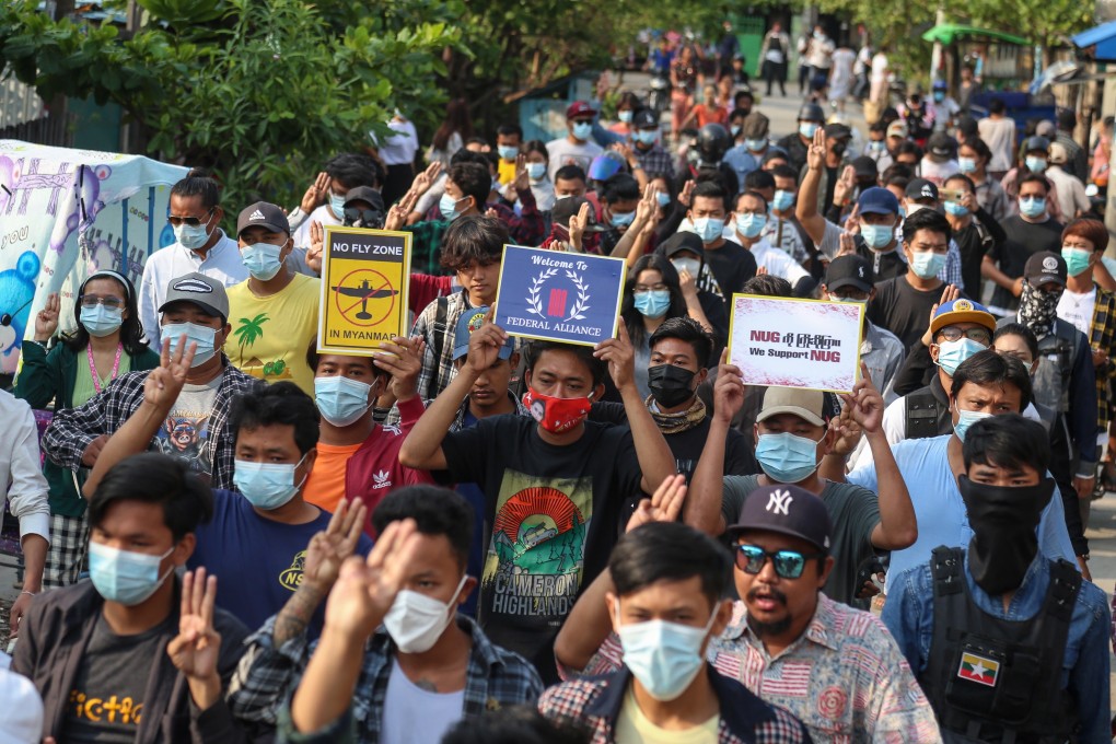 Demonstrators carry placards and flash the three-finger salute during an anti-coup protest in Mandalay on Monday. Photo: EPA-EFE