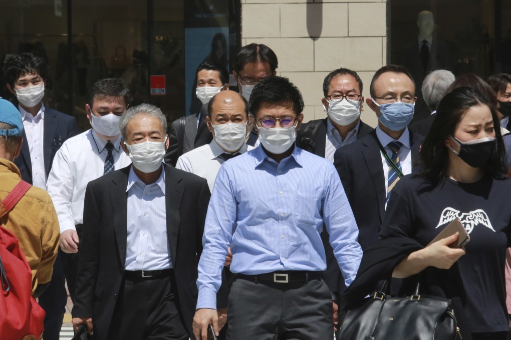 People wearing face masks to protect against the spread of the coronavirus walk on a street in Tokyo on Tuesday. Photo: AP