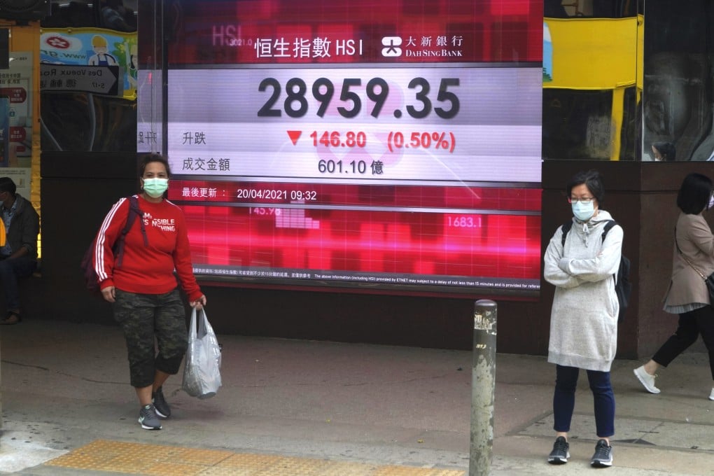 People wearing face masks stand in front of a banks electronic board showing the Hang Seng Index near Central, Hong Kong. Photo: AP
