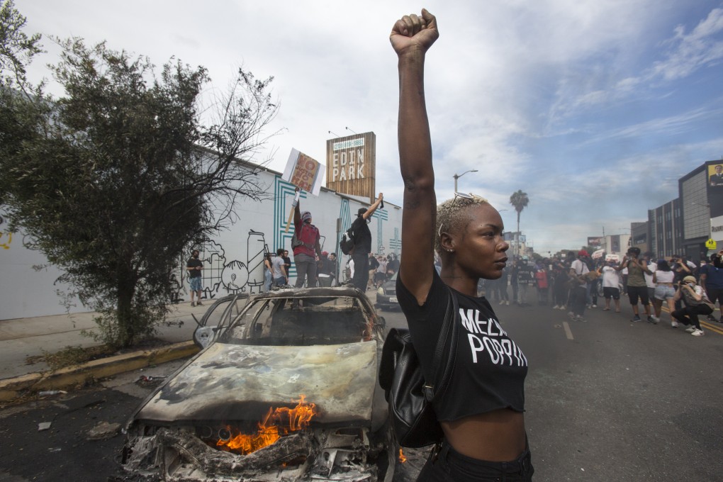 A protester poses stands next to a burning police vehicle in Los Angeles in May 2020 during a demonstration over the death of George Floyd. Photo: AP