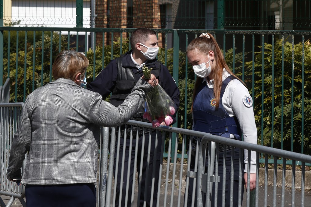 A woman hands flowers to a police officer to be taken down to the police station where a official was stabbed to death in Rambouillet. Photo: AP