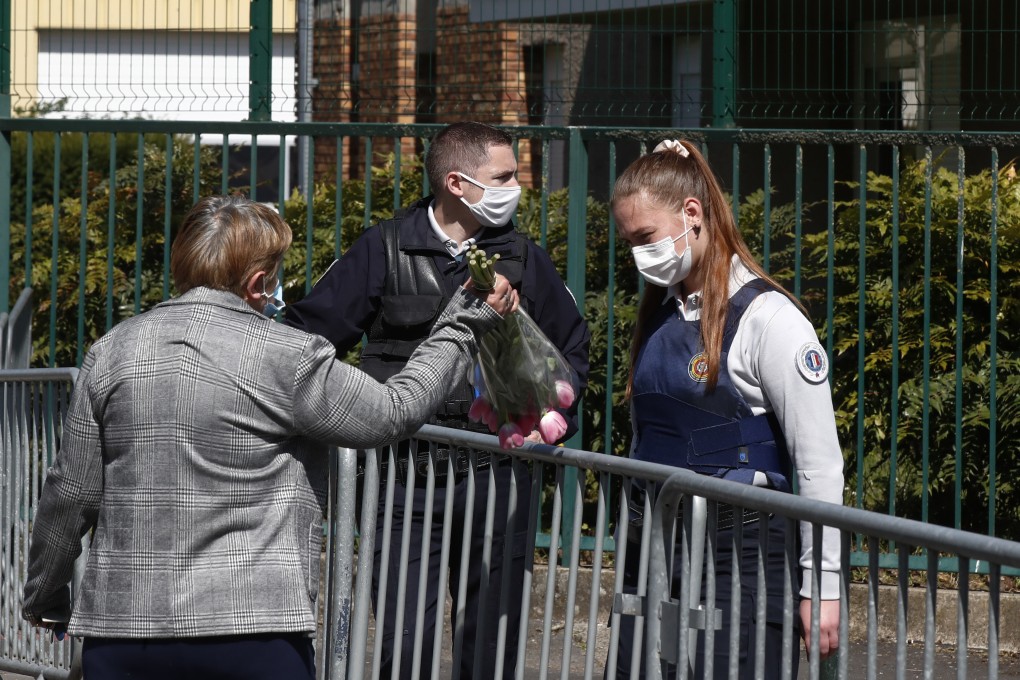 A woman hands flowers to a police officer in Rambouillet, near Paris, on Saturday. Photo: AP