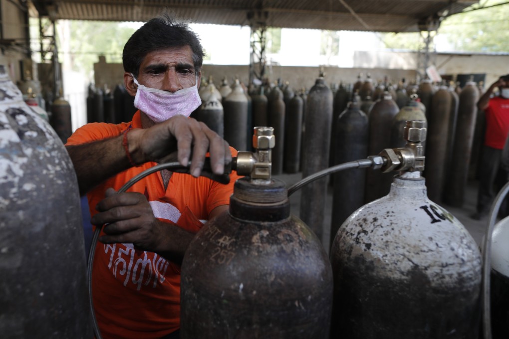 A worker refills medical oxygen cylinders at a charging station on the outskirts of Prayagraj, India. Photo: AP