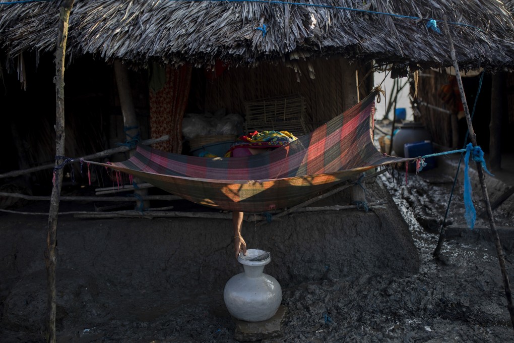 A woman collects drinking water from a dew-damp cloth in the village of Kalabogi in Bangladesh on the morning of September 27, 2020. Photo: World Press Photo