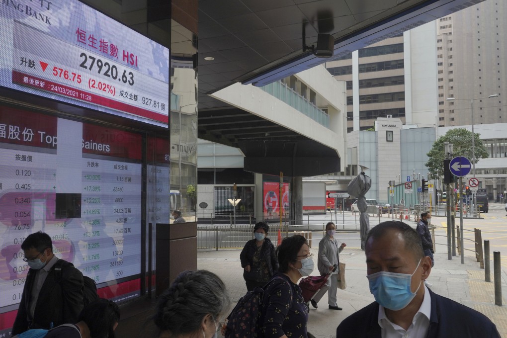 People walk past a bank’s electronic board showing the Hang Seng index in Hong Kong on March 24. Photo: AP