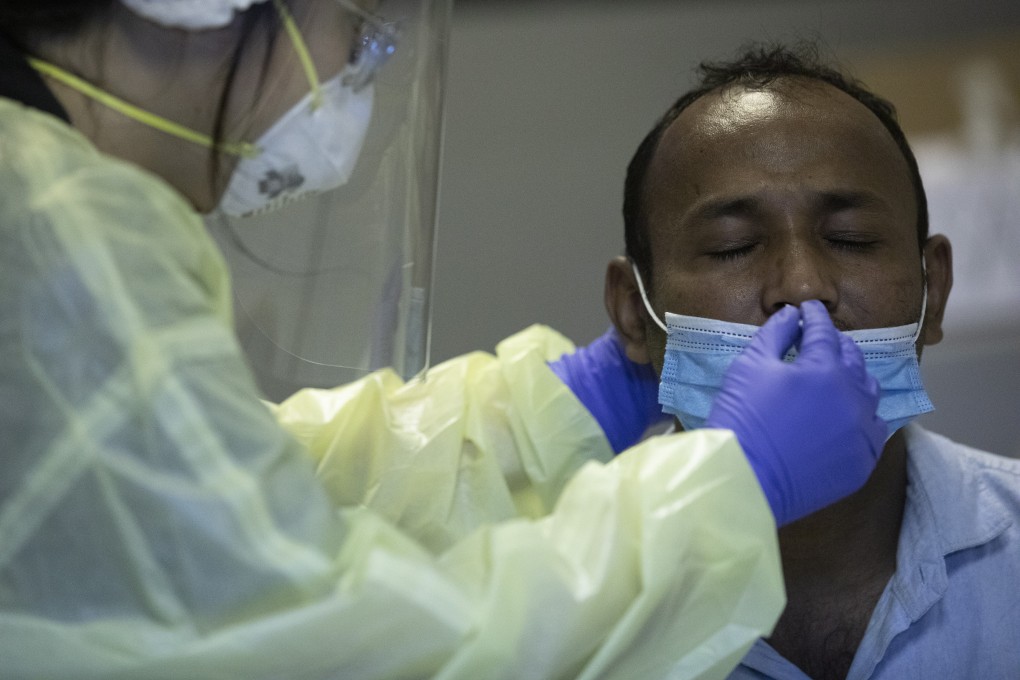 In Singapore, a volunteer performs a coronavirus swab test on a migrant worker. Photo: EPA